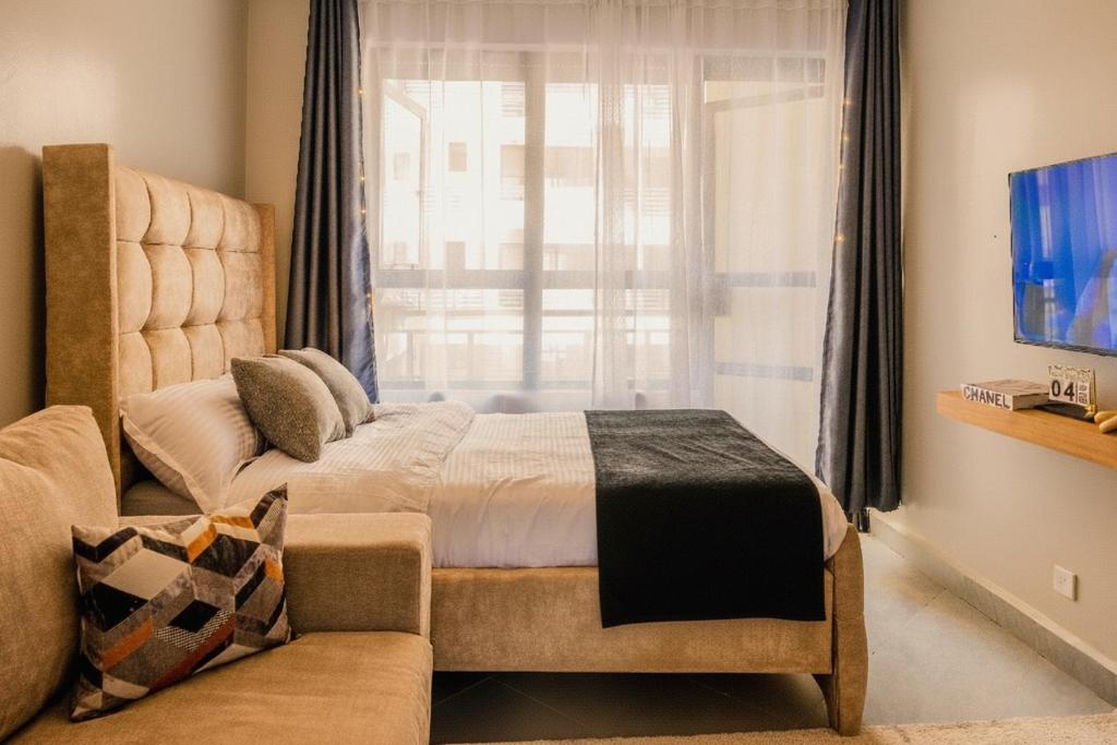 ein Schlafzimmer mit einem Bett und einer Couch und einem Fenster in der Unterkunft Navira Studio with Pool in Nairobi