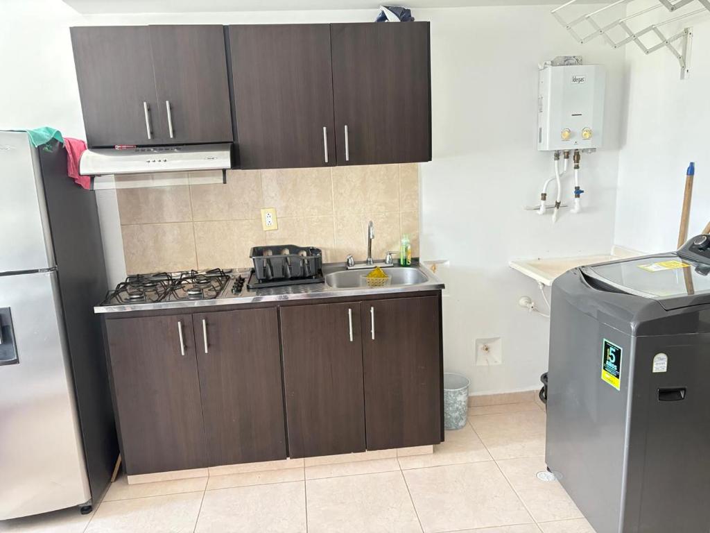 a kitchen with brown cabinets and a sink and a refrigerator at apta estudio oronegro amanecer in Armenia