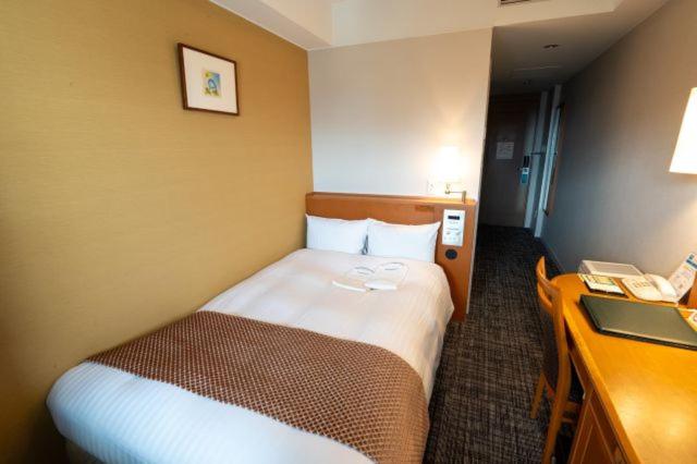 una camera d'albergo con un letto e una scrivania di Toshi Center Hotel a Tokyo