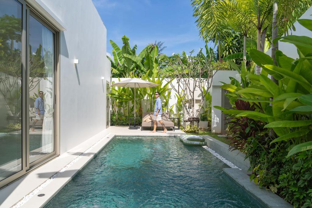 a pool in a house with a woman standing next to it at Coco Villas Phuket - Private Pool Villas by Escape Villas in Thalang
