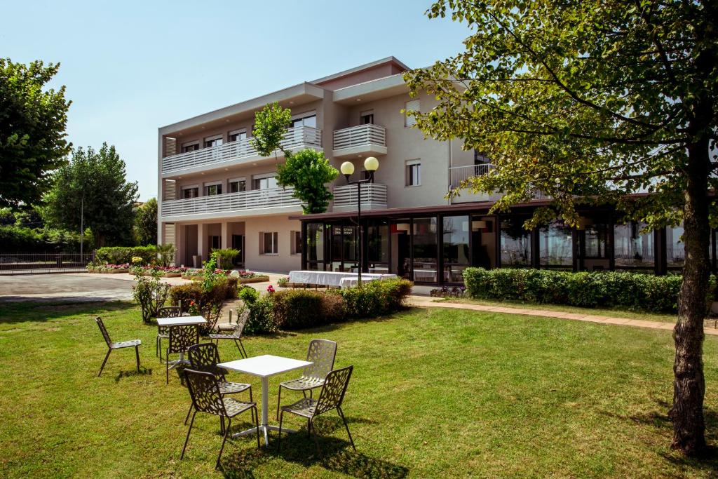 a building with tables and chairs in a yard at Hotel Stella del Benaco in Manerba del Garda
