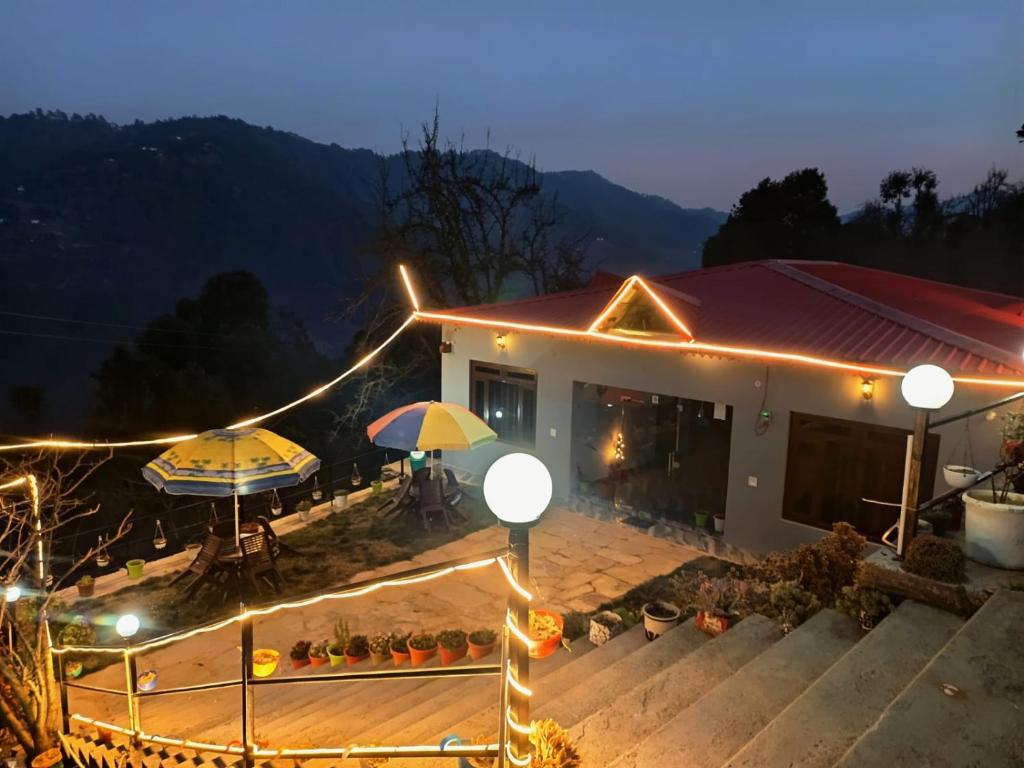 une maison avec deux parasols et une terrasse la nuit dans l'établissement A Home Above the Clouds Riturain Mukteshwar, à Mukteswar
