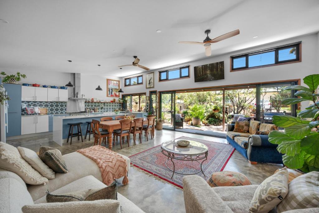 a living room with couches and a table and a kitchen at Hyams Reach Retreat in Erowal Bay