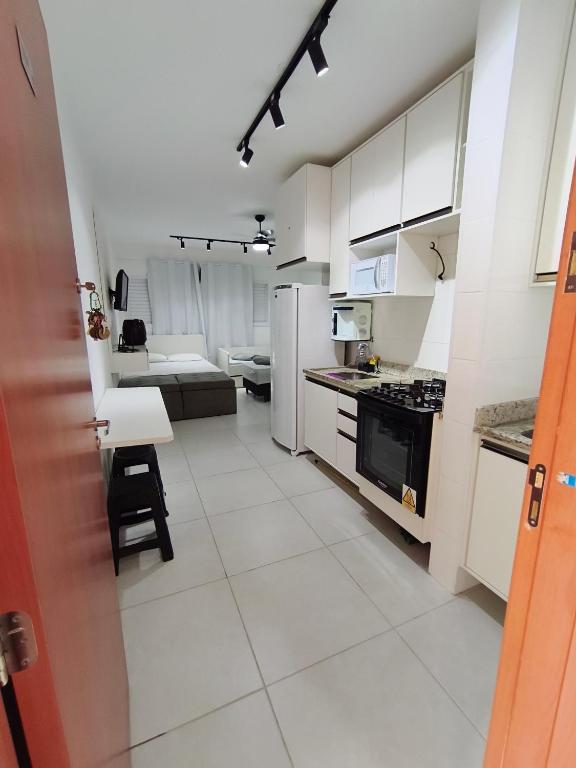 a kitchen with white cabinets and a white tile floor at 2 Evangelistas Apartamentos in Cachoeira Paulista