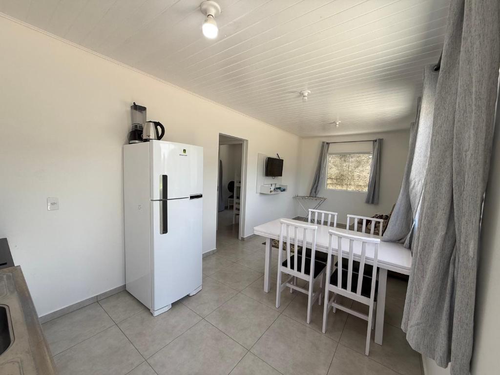 een keuken met een witte koelkast en een tafel en stoelen bij Casa nova bem aconchegante e tranquila in Biguaçu