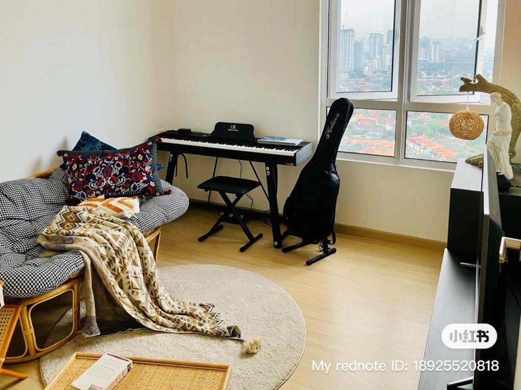 a living room with a piano and a chair with a blanket at Simple and nice unit 3 bed 2 bath in Petaling Jaya