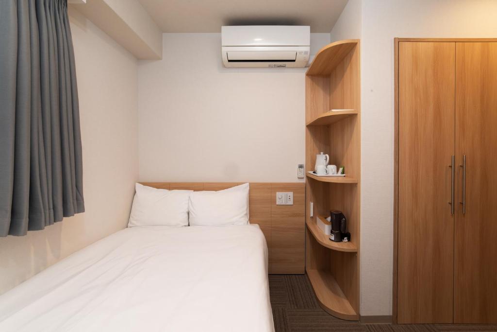 Kleines Zimmer mit einem Bett und einem Schrank in der Unterkunft Hopetree 天王寺 in Osaka