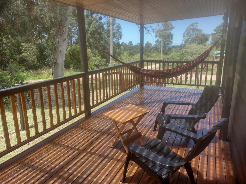 eine Veranda mit 2 Stühlen, einem Tisch und einer Hängematte in der Unterkunft Chalet Bilu in Piriápolis