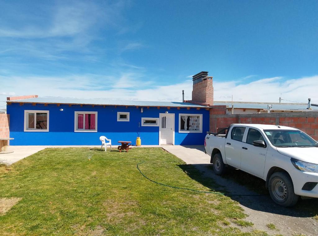 een witte truck geparkeerd voor een blauw huis bij wind house - casa del viento in Perito Moreno