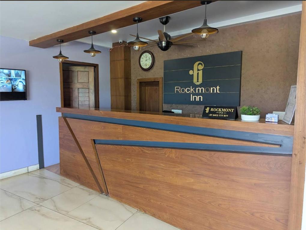 a front desk of a restaurant with a clock on the wall at Rockmont Inn in Taliparamba