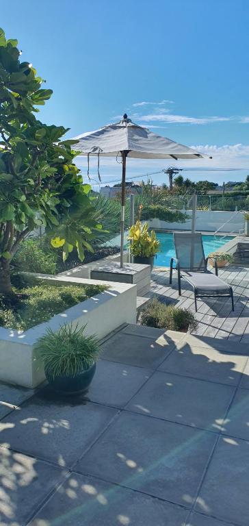 a patio with a table and an umbrella and a pool at Stillpoint Retreat in Motungarara