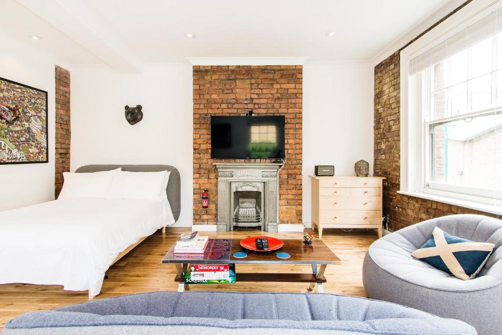 a living room with a bed and a fireplace at Crashpads Shoreditch Brick Lane Mini Lofts in London