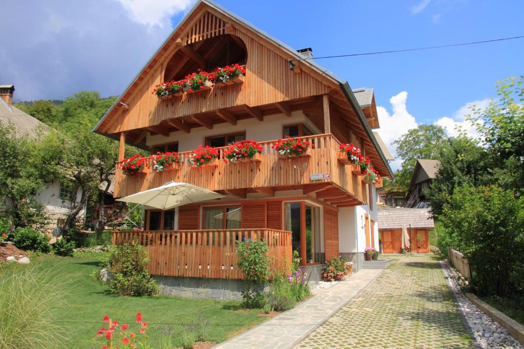 una casa con un balcón con flores rojas. en Apartments Vila Jelka, en Bohinj