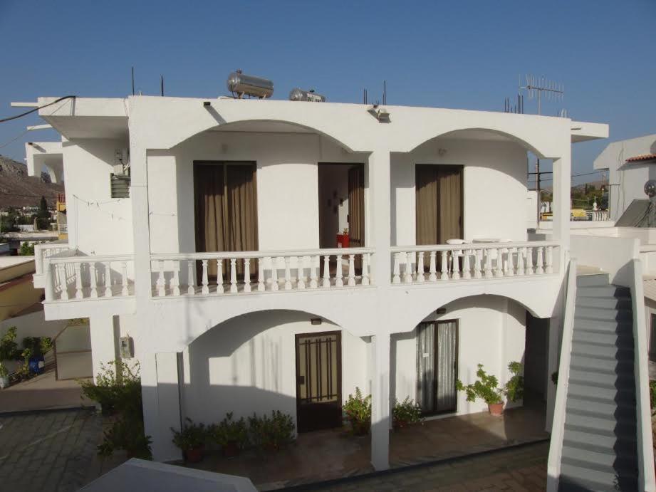 a white building with a balcony on top of it at Pension Annoula in Archangelos