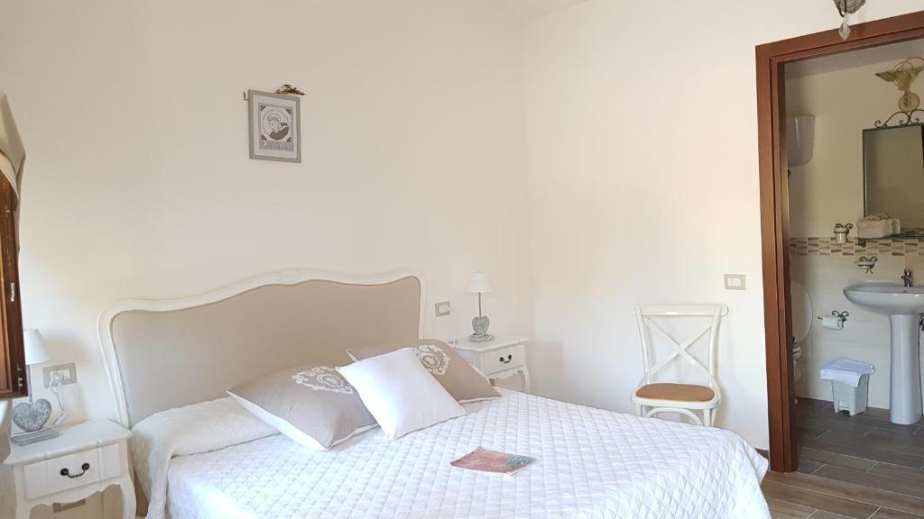 ピアーノ・デッレ・ピエーヴェにあるIl Gelso Assisiの白いベッドルーム(ベッド1台、鏡付)
