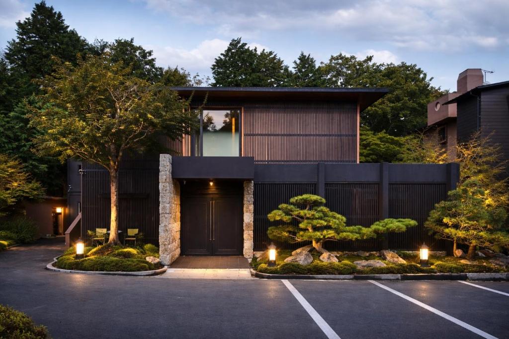 a house with a black door in a parking lot at Hakone Hibarino hot spring hotel in Hakone