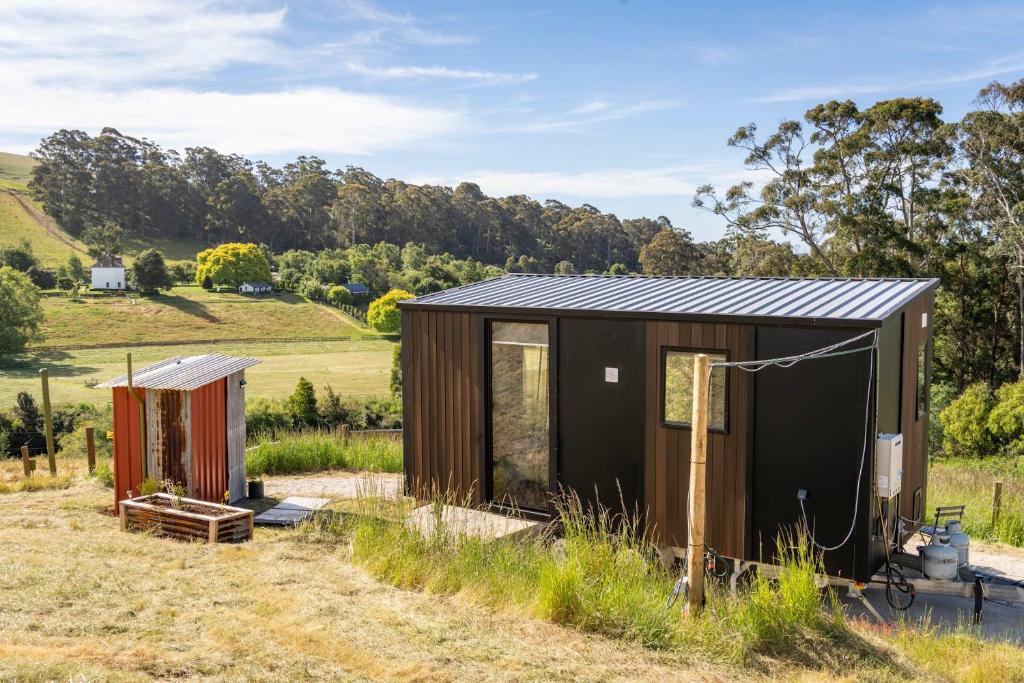 a small house in a field with two buildings at Perrys North by Tiny Away in Forth