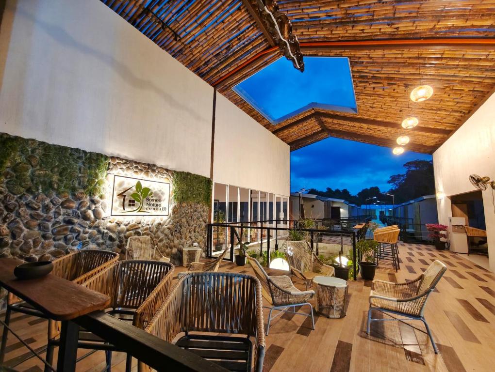a patio with chairs and tables and a stone wall at Borneo Nature Lodge 2 in Kinabatangan