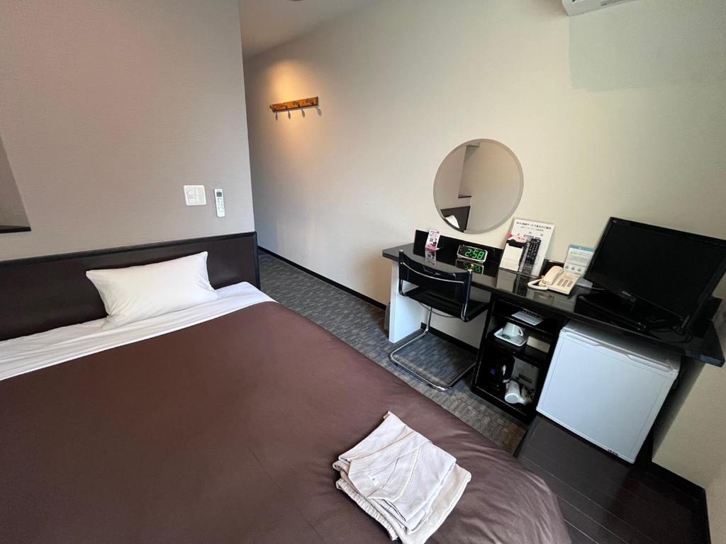 een hotelkamer met een bed en een bureau met een spiegel bij Urbain Hiroshima Executive in Hiroshima