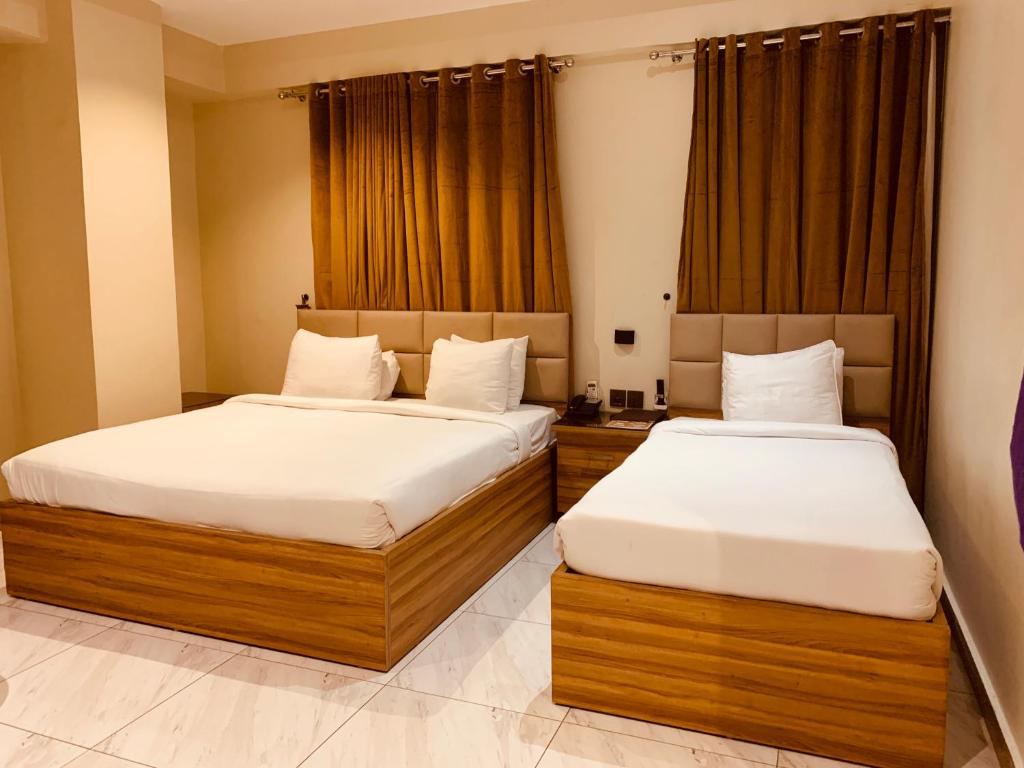 two beds in a hotel room withskirts at Hotel pearlinn karachi in Karachi