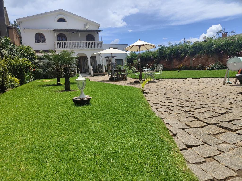 a house with a grass yard with a cobblestone driveway at Faly madatour GH in Antsirabe