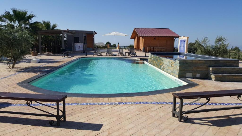 uma piscina com dois bancos e um edifício em Agriturismo Duca di San Martino em Partanna