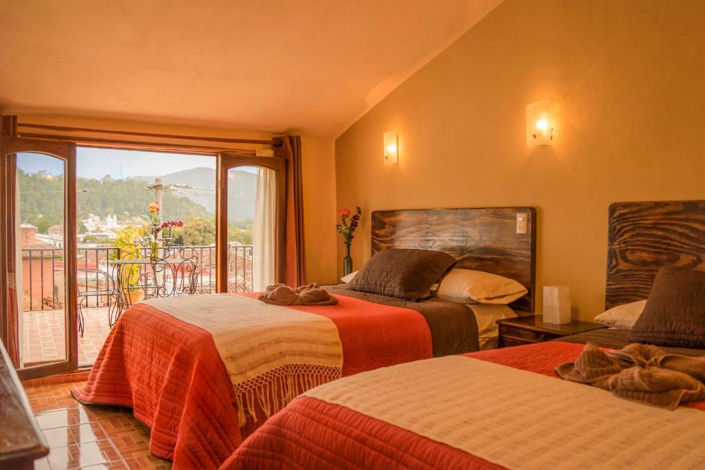 1 dormitorio con 2 camas y ventana grande en Hotel Posada Dominnycos en San Cristóbal de Las Casas