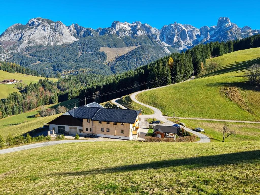 a house on a hill with mountains in the background at Ferienwohnungen Unterdürmoos Apartments mit Chalet-Charme auf 1050 m , Alleinlage in Annaberg im Lammertal