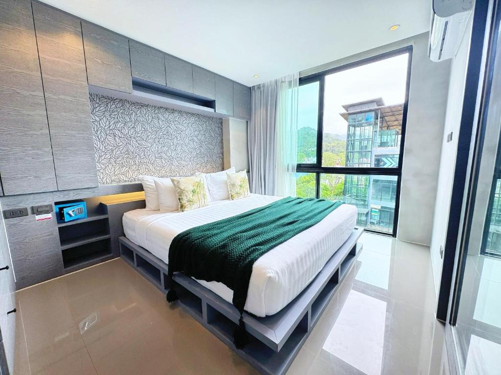 a bedroom with a bed and a television in it at Modern Urban Living Kamala in Kamala Beach