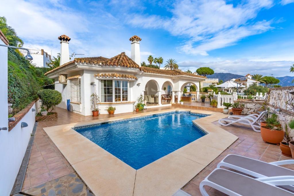 a villa with a swimming pool in front of a house at Villa Cempo V215 in La Cala de Mijas