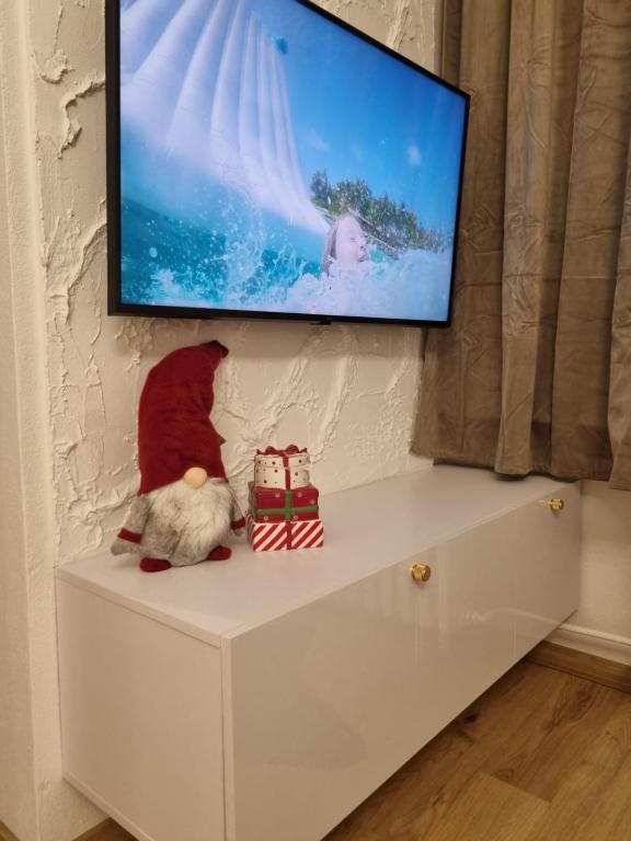 Een kat zit op een dressoir met een tv aan de muur. bij Apartmán Sárka Brezno in Brezno