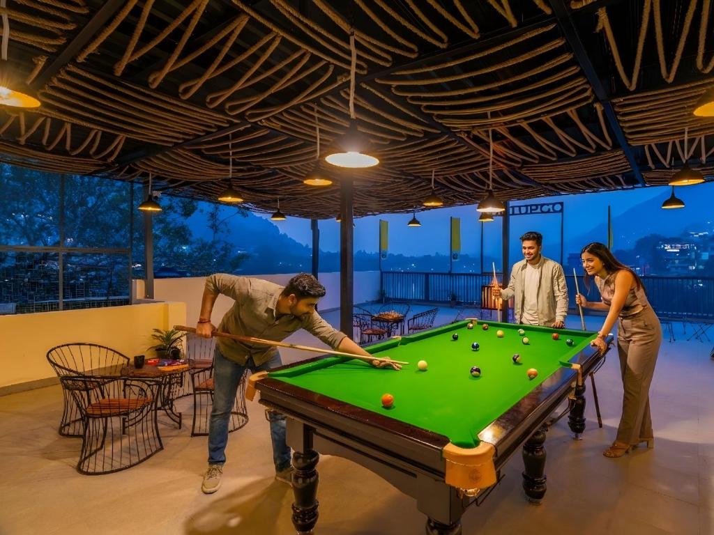 eine Gruppe von Menschen, die eine Partie Billard spielen in der Unterkunft The Hosteller Rishikesh, Laxman Jhula in Rishikesh