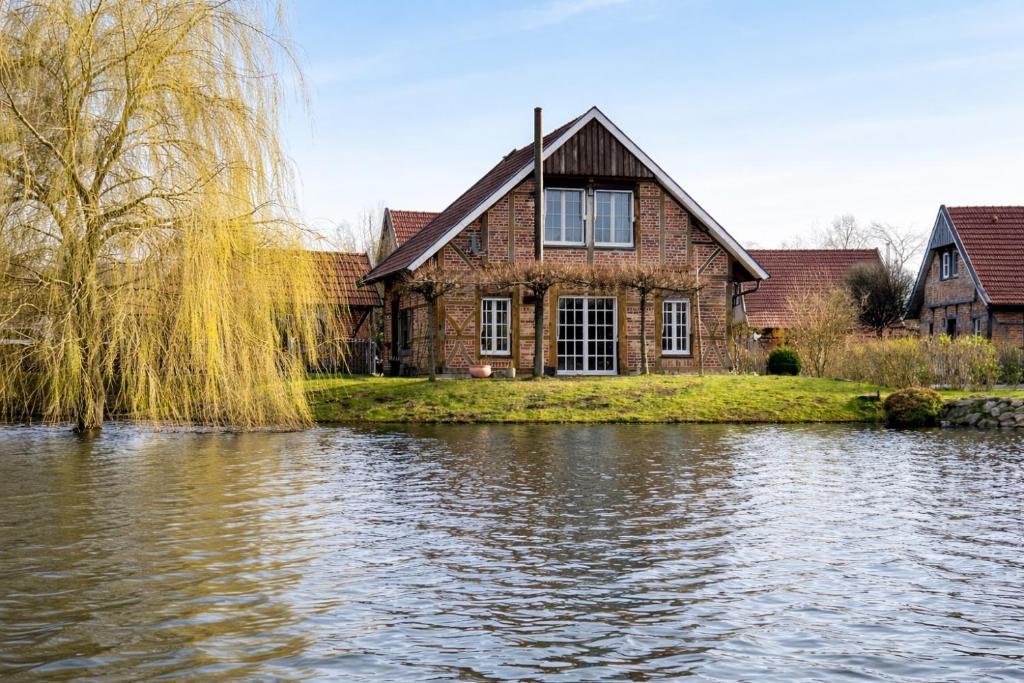 une maison à côté d'une rivière avec un arbre dans l'établissement Gemütliches Fachwerkhaus am See mit Kamin, à Warendorf