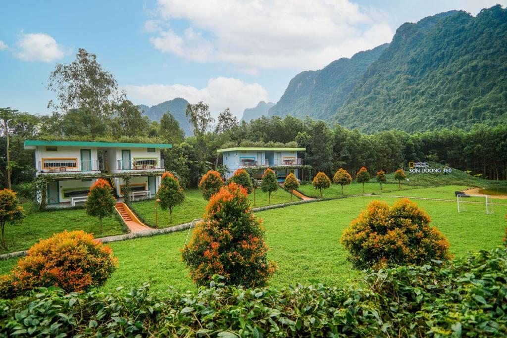 ein Haus auf einem Feld mit Bergen im Hintergrund in der Unterkunft Chay Lap Farmstay Phong Nha in Ðá Lòn