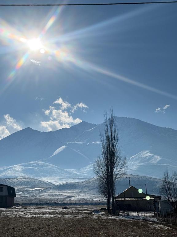 een zon in de lucht met bergen op de achtergrond bij Gulbara Guest House in Toguz-Bulak