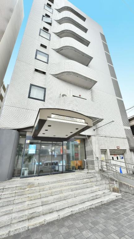 a tall white building with stairs in front of it at First Inn Haiki in Sasebo