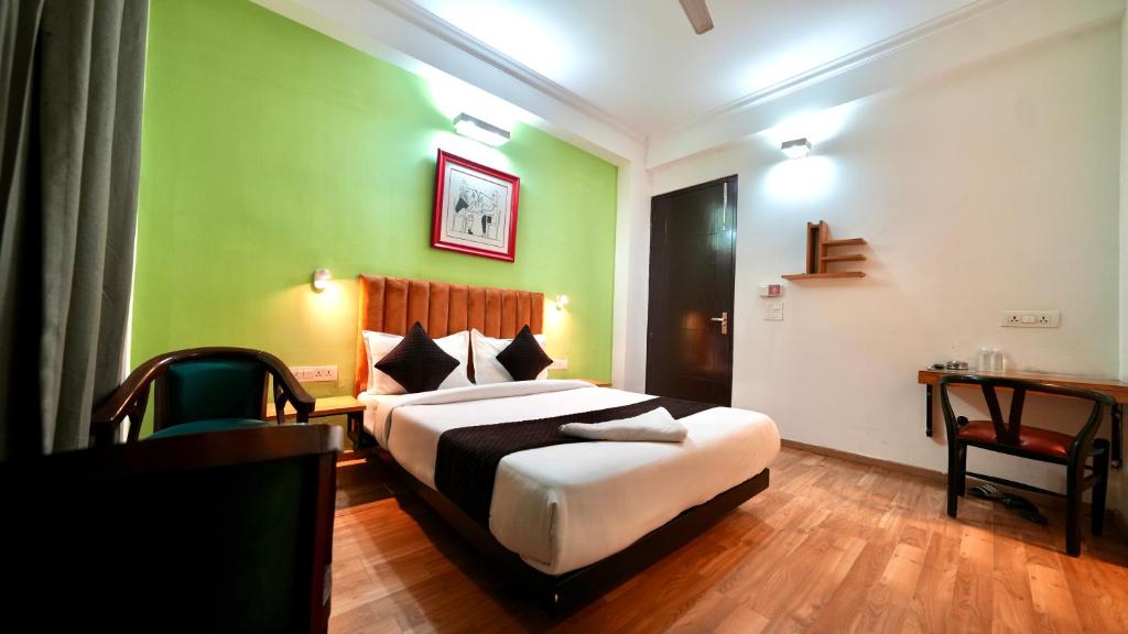 a bedroom with a bed with green walls and a desk at Hotel Rustam Residency sec-39 in Gurgaon
