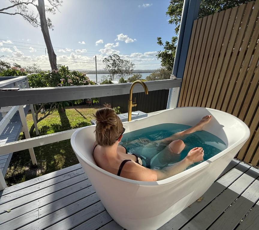 a woman laying in a bath tub on a deck at Lakeview Cottage in Forster