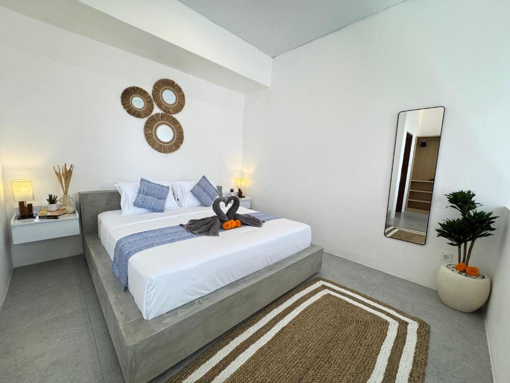 a white bedroom with a large bed and a mirror at Manik Tropicana Loft in Canggu