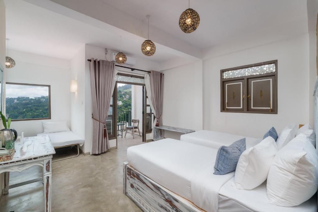 a white bedroom with a bed and a couch at Earthbound Residence- Kandy in Kandy