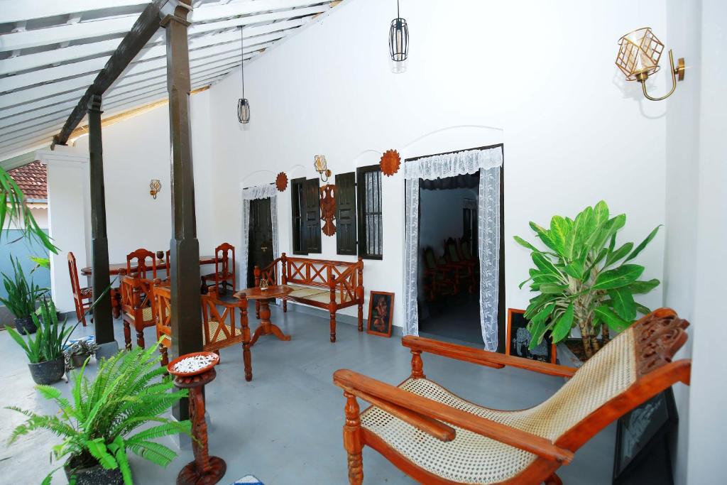 a porch with wooden benches and a table and chairs at Kandy House Hiriketiya in Dickwella