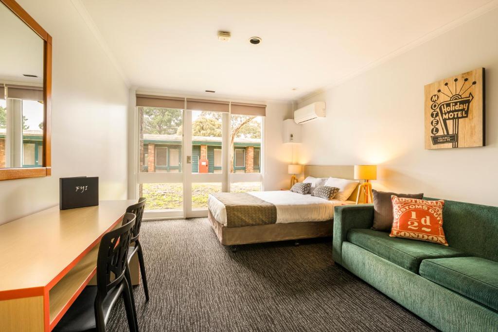 1 dormitorio con 1 cama y 1 sofá verde en Burvale Hotel, en Nunawading