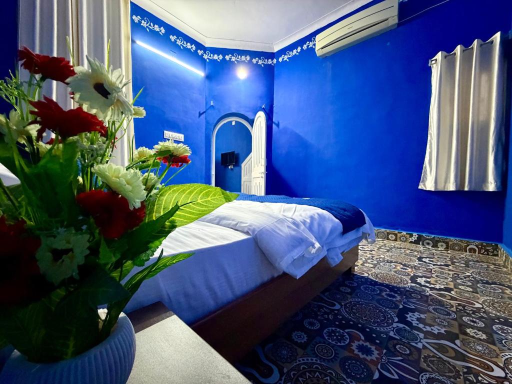 a blue bedroom with a bed with flowers in a vase at Brij niwas in Udaipur