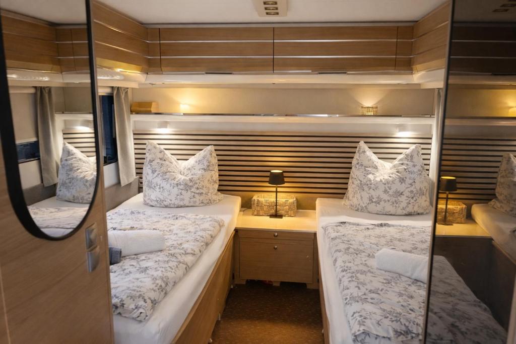 2 bedden in een kleine kamer met een bureau bij Weberhof-Münster Glamping in Münster