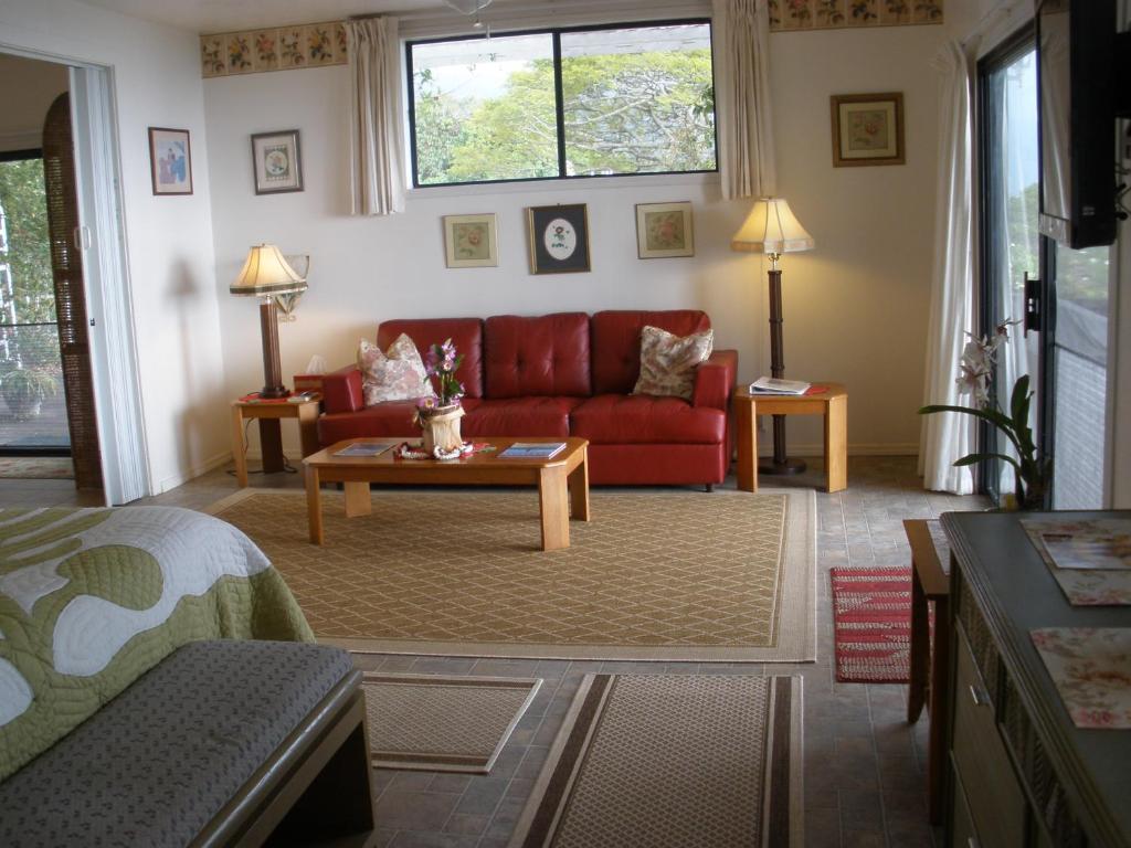 a living room with a red couch and a table at Belle Vue Kona Inc in Captain Cook
