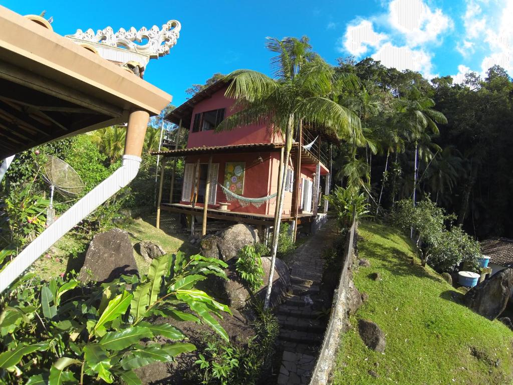 uma pequena casa vermelha numa colina ao lado de um edifício em Chalé do Félix em Ubatuba