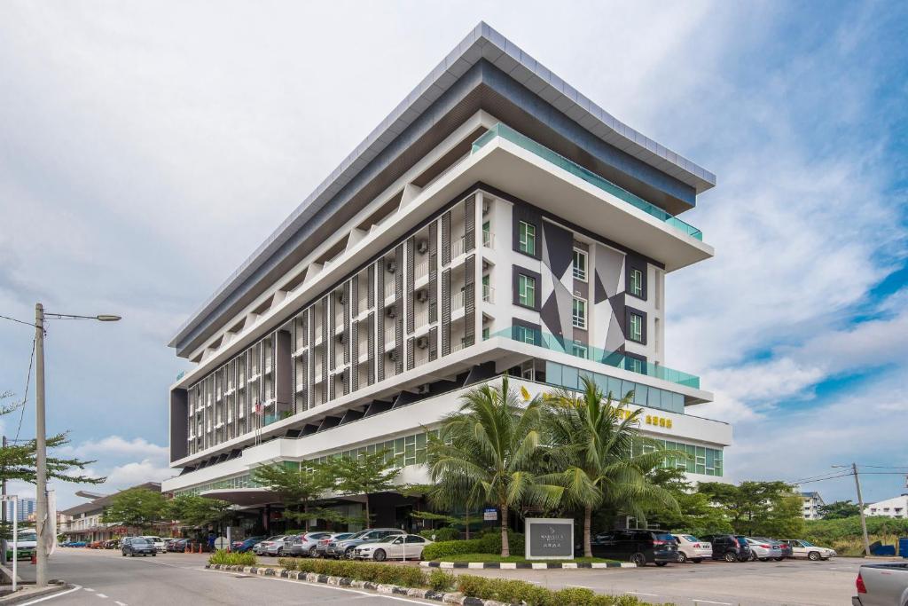 a tall building with cars parked in a parking lot at Marvelux Hotel in Malacca