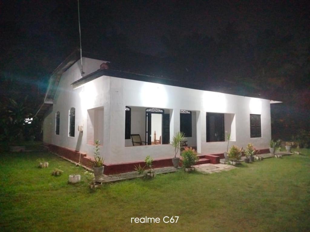een klein wit huis met een tuin in de nacht bij Villa77 Benthota in Bentota