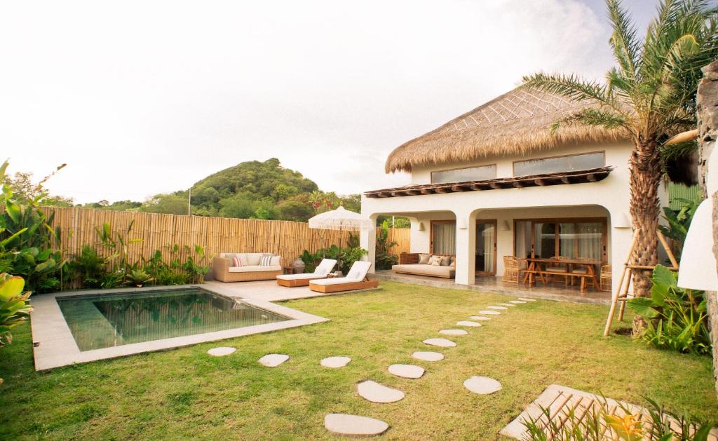 een achtertuin met een zwembad en een huis bij Irama Surf Villas in Sekongkang Bawa