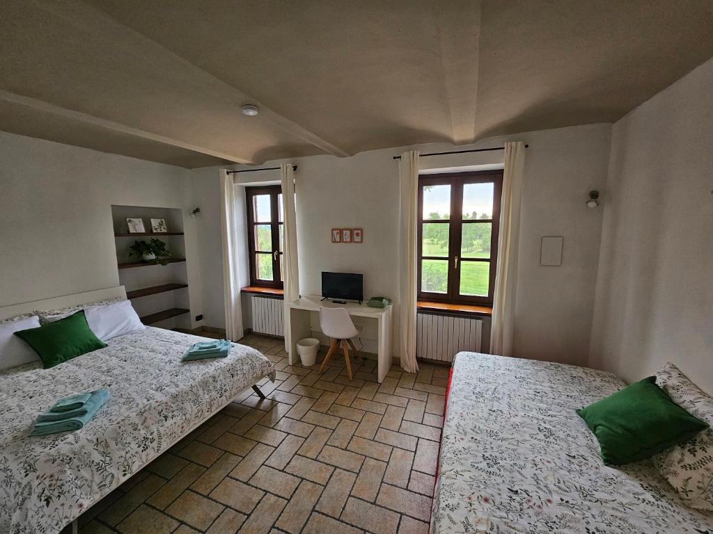 een slaapkamer met 2 bedden, een bureau en 2 ramen bij B_B La Rugiada in Tigliole